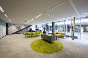 Modern office space at Jacob Bontiusplaats with bright furniture, wall art, and large windows.
